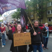 Zwei Aktivist*innen mit einer junges Attac- und einer Antifa-Fahne auf der Demo. Die Aktivistin hält ein Schild mit dem Slogan "Antifa geht analog, schmeißt die Nazis in den Woog!"