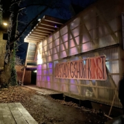 Bild der Main-Hall auf dem Osthang mit einem Banner mit der Aufschrift "Die Stadt gehört Kunst" bei der in Kunst das Wort "uns" farblich hervorgehoben ist